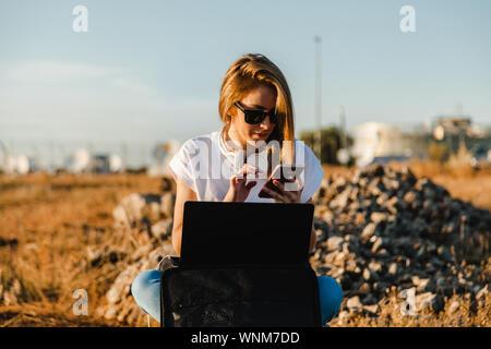 Jeune femme avec son portable communique avec les antennes dans le domaine Banque D'Images