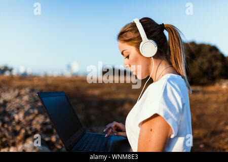 Jeune femme avec son portable communique avec les antennes dans le domaine Banque D'Images