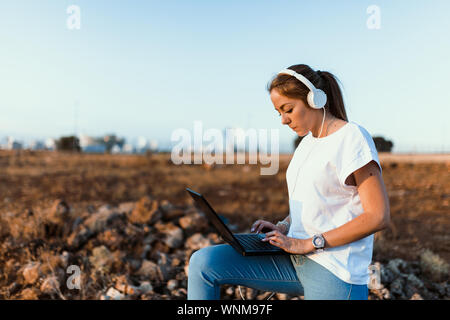 Jeune femme avec son portable communique avec les antennes dans le domaine Banque D'Images