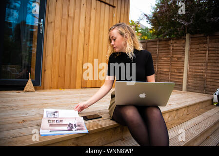 Travail de la maison modèle sur ordinateur portable avec du bois de cèdre plaqués en arrière-plan de construction Banque D'Images