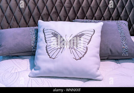 Coussin en cuir blanc avec papillon brodé à l'intérieur chambre à coucher. Banque D'Images