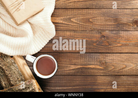 Composition d'automne. Cadre fait de blanc chandail tricoté, tasse de thé, du bois sur fond de bois. Automne ou hiver confortable maison de concept. Télévision lay, t Banque D'Images