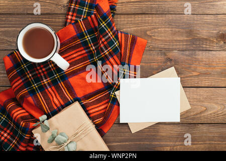 Composition d'automne. Cadre fait de l'écharpe en tricot rouge, Lettre, carte de papier vierge, tasse de thé, de boîte-cadeau sur fond de bois. Maison de vacances d'hiver ou d'automne douillet c Banque D'Images