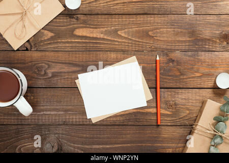 Flatlay avec composition d'automne lettre, papier blanc, tasse de thé, boîte-cadeau, enveloppe, bougies sur fond de bois. Maison de vacances d'hiver ou d'automne agréable Banque D'Images