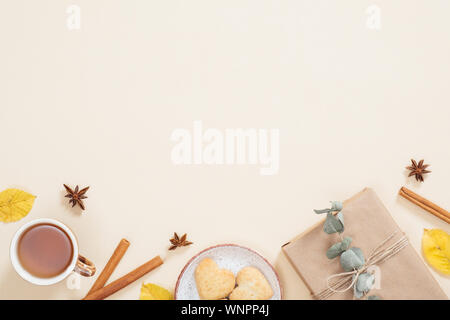 Flatlay composition d'automne. Cadre fait de tasse de thé, l'automne les feuilles sèches, les bâtons de cannelle, cookies, boîte-cadeau sur fond beige pastel. Mise à plat, haut Banque D'Images