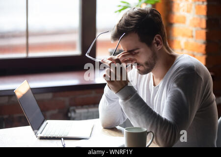 L'homme bouleversé le massage du nez, en verres, sentiment de fatigue oculaire Banque D'Images