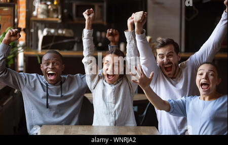 Divers amis, excité les fans de football, célébrant la victoire but en cafe Banque D'Images