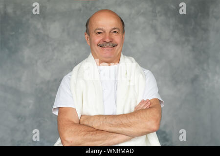 Soins du corps le matin. Hisanic Senior homme après le rasage debout avec serviette blanche et souriant. Banque D'Images