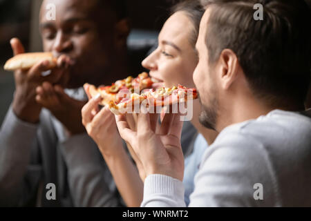 Close up professionnels divers friends eating pizza dans cafe ensemble Banque D'Images