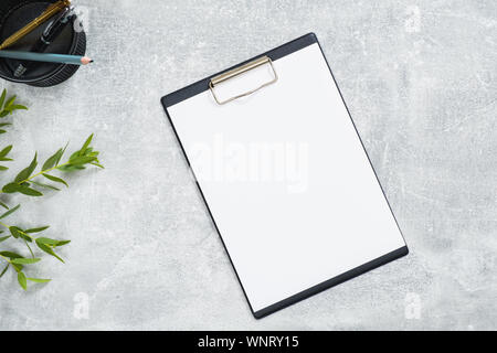 Presse-papiers papier vierge sur le béton maquette 24 avec modèle et de branche avec des feuilles vertes. Mise à plat, vue du dessus, les frais généraux. Concept d'entreprise. Banque D'Images