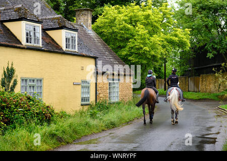 Deux jeunes femmes pilotes sur l'on country lane à Chipping Campden three ways House en Angleterre après une pluie Banque D'Images