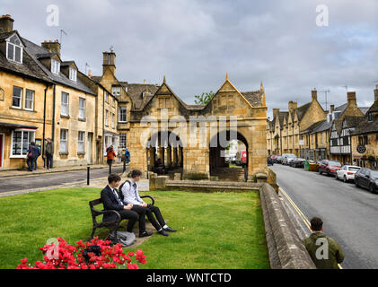 Les étudiants et les touristes à l'heure du déjeuner du marché du 17ème siècle avec Hall en pierre jaune de Cotswold sur High street Chipping Campden Angleterre Banque D'Images