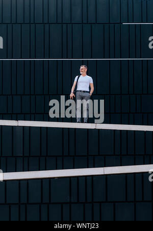 Homme barbu adultes avec bandoulière sac debout contre le mur de la ville Banque D'Images