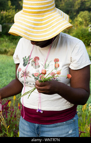 Femme noire avec chapeau jaune et fleurs réductions écouteurs dans le domaine Banque D'Images