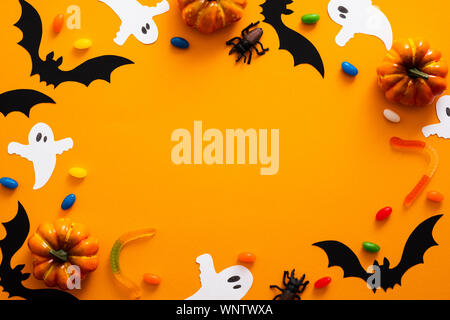 Happy Halloween de concept. Décorations d'Halloween, citrouilles, chauves-souris, des bonbons, des fantômes, des bugs sur fond orange. Halloween party maquette de carte de vœux Banque D'Images