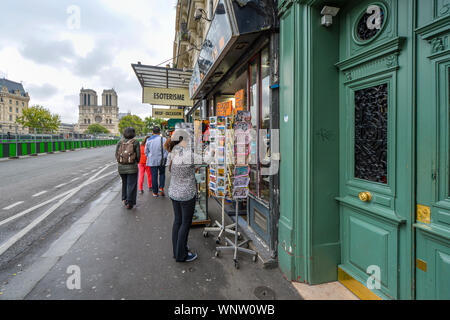 Un touriste recherche les cartes postales à Paris, en France, à un trottoir magasin de souvenirs sur les bords de la Seine avec la Cathédrale Notre Dame de la Banque D'Images