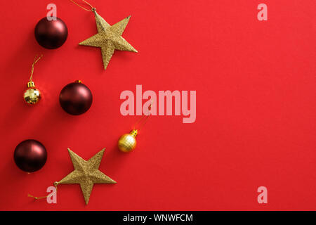 Décorations décorations de Noël sur fond rouge avec l'exemplaire de l'espace. Mise à plat des boules de noël, étoiles d'or, scintillant de confettis. Maquette de couverture de Noël, Banque D'Images