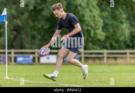 Jeune homme rugby player (âge 150-25 ans) fonctionnant avec ballon de rugby dans la main tendre la main pour marquer un essai. Banque D'Images