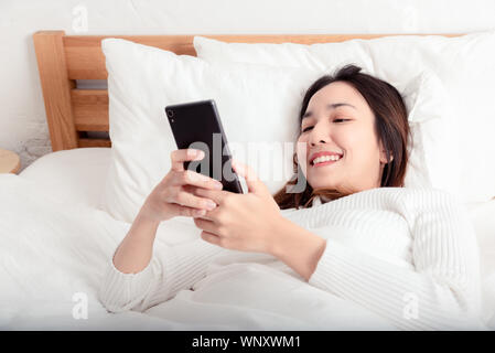 Mains de femme fermé jusqu'chat médias sociaux sur mobile phone on lit dans la chambre pour le réveil matin, temps de vie.Avec la technologie concept gadget Banque D'Images