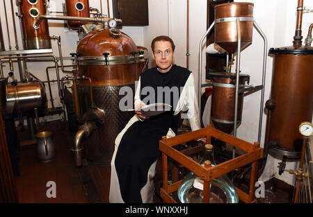 04 septembre 2019, Bochum, Rhénanie du Nord-Westphalie : Père Justinus se trouve dans la distillerie, est titulaire d'une pelle de mesure avec les baies de genièvre dans ses mains et regarde dans la caméra du photographe, produit sa propre preuve de gin et l'appelle "onatic Dry Gin'. Les herbes qu'il a besoin sont plantées et récoltées dans le jardin du monastère. Il obtient le genévrier de Toscane et le grain d'où l'alcool est obtenu qu'il obtient de l'abbaye de Heiligenkreuz mère dans la forêt viennoise. Dans le monastère lui-même il n'est pas autorisé à brûler de gin, parce qu'il n'a pas de droits de distillation. Pour cela, il driv Banque D'Images