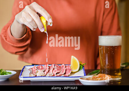 Maintenez les mains avec du jus de lime lime sur tranches de contre-filet grillé bifteck rare. Banque D'Images