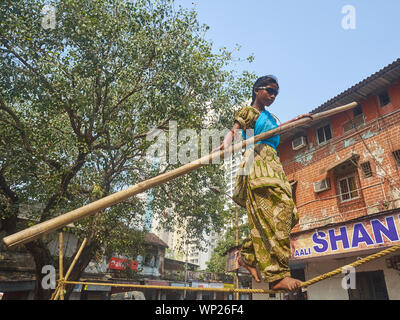 Une jeune fille à Mumbai, Inde, avec des lunettes non transparent en équilibre sur une corde raide, dans un soi-disant "tamasha' ou improvisés street circus Banque D'Images