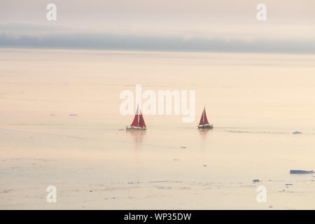 Croisière voilier rouge parmi des icebergs dans la baie de Disko glacier durant la saison de soleil de minuit de l'été polaire. Ilulissat, Groenland. L'Unesco Banque D'Images