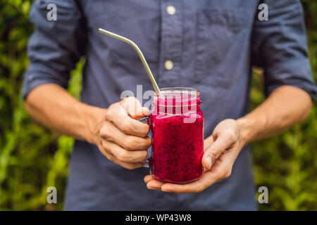 Smoothie aux fruits du dragon en acier avec paille dans les mains des hommes Banque D'Images