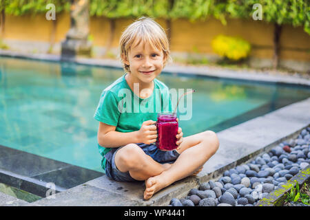 Garçon dragon boissons de fruits avec de l'acier paille de la piscine Banque D'Images