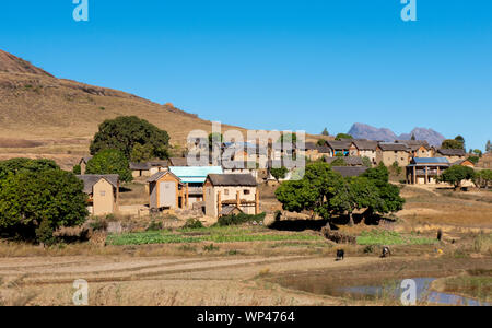 Petit village dans le sud-ouest de Madagascar highlands typique construite en brique avec des maisons de chaume de la culture du riz et les montagnes Banque D'Images