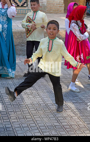 Boukhara, Ouzbékistan. Un jeune garçon danse et habillés en costume traditionnel ouzbek et russe, lors d'une célébration de la culture russe et ouzbek. Banque D'Images