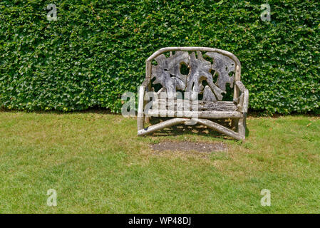 Rustique, décoré en bois, banquette de jardin fabriqué à partir des pièces en bois, en face d'un mur de plantes vertes - Berkshire, Royaume-Uni Banque D'Images