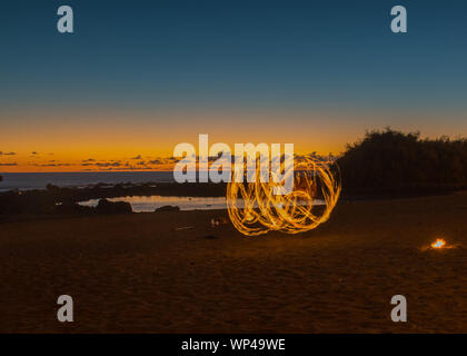 Dans la danse du feu sur la plage au crépuscule après le coucher du soleil de la plage de la ville de Valle del Rey, La Gomera, Canary Islands, Espagne, en octobre. Banque D'Images