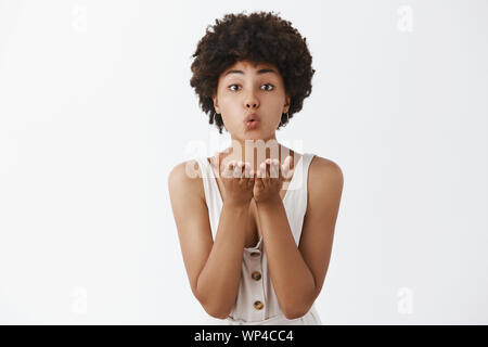 En attente de l'amour vrai à venir. Portrait de l'adjudication et mignon charmant African American Woman with curly hairstyle, lèvres et holding palms près de m Banque D'Images