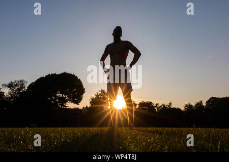 Un garçon prendre et transmettre un ballon de rugby sur une journée d'été dans un parc, de formation pour la nouvelle saison Banque D'Images