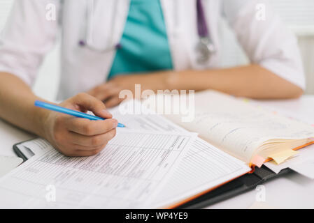 Close-up of woman doctor in office de remplir formulaire de demande Banque D'Images