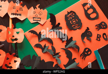 De l'artisanat pour l'halloween concept. Les chiffres d'un black bat et fantômes, une guirlande de citrouilles avec Visages, cut out de noir et orange sur papier Banque D'Images