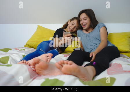 Soeurs partageant un moment cocasse à à à mobile smartphone. Banque D'Images