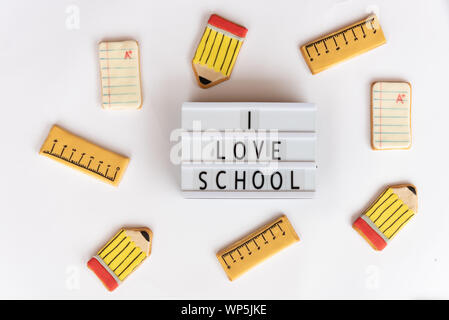 Concept Retour à l'école. Le texte que j'aime l'école dans une lightbox sur fond blanc et entouré par les cookies de fondant avec des conceptions relatives à l'école li Banque D'Images