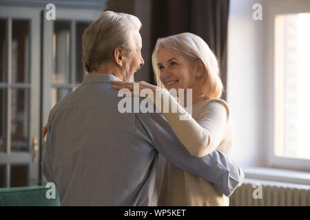 Smiling mature couple dansant ensemble célébrer à la maison Banque D'Images