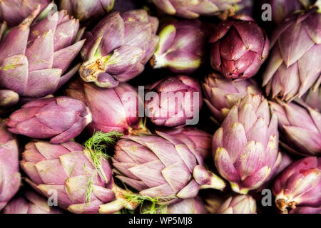 Bande d'artichauts violets au hasard en tas à un marché de producteurs