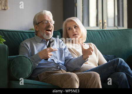 Agacé elder woman cheering couple, regarder la télévision. Banque D'Images