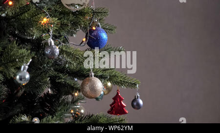 Boules de Noël jouets décoratifs se joue sur la branche de l'arbre vert artificiel, copyspace Banque D'Images