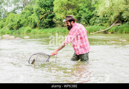 Zone de pêche. pêcheur avec canne à pêche pêcheur barbu. dans l'eau. week-end d'été. La pêche au gros. mature man fly fishing. man la capture de poissons. passe-temps et les activités sportives. pothunter. Banque D'Images