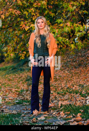 Création pour agréable fin de semaine. Adorable petite fille blonde posing in outfit chaleureux et cosy de l'automne nature fond flou. L'heure du coucher du soleil à pied femme. Tenues décontractées confortable pour la fin de l'automne. L'ambiance chaleureuse et confortable. Banque D'Images