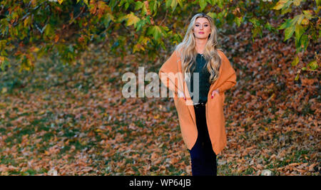 Création pour agréable fin de semaine. Femme à pied. La lumière au coucher du soleil Tenue confortable. Adorable petite fille blonde posing in outfit chaleureux et cosy de l'automne nature fond flou. Tenues décontractées confortable pour la fin de l'automne. Banque D'Images