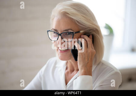 Smiling senior woman in glasses parler on cellphone Banque D'Images