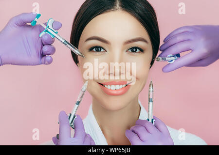 Concept publicitaire femme asiatique de rajeunissement de la peau à l'aide d'injection de beauté sur fond rose. lot de seringues autour d'un visage de femme non-chirurgicale. Banque D'Images