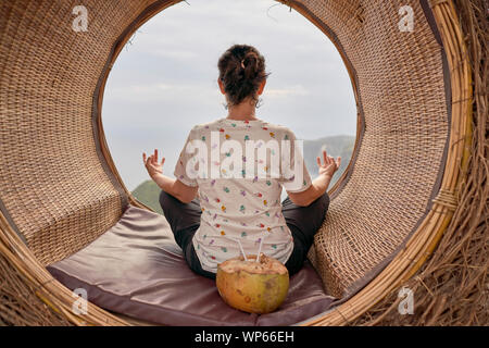 Jeune femme de prendre une pause et de boire une noix de coco au bord de la mer, Bali, Indonésie Banque D'Images