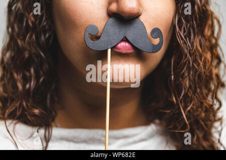 Close up portrait of head shot of young girl wearing fake moustaches - Girl holding funny moustache sur stick Banque D'Images